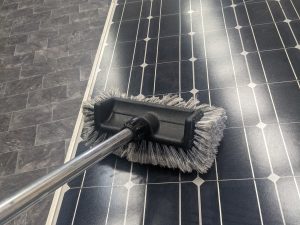solar installer cleaning solar panels with a brush